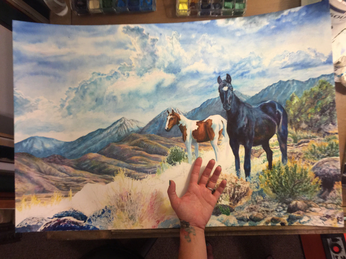 Mustangs Wild original watercolor in progress with the artist’s hand showing the scale of the 20 by 30 inch painting