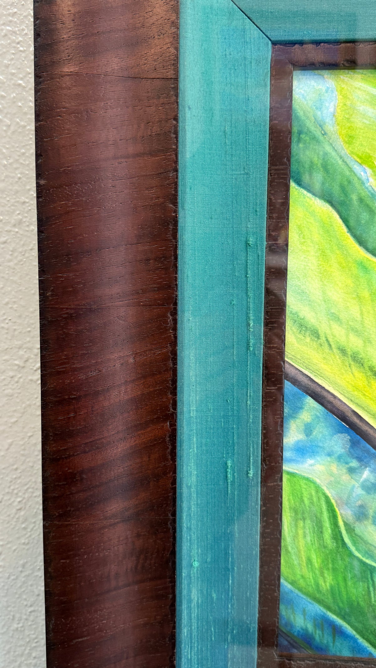 Close-up of the dark wood frame and turquoise silk-wrapped liner surrounding Tropical Flame

