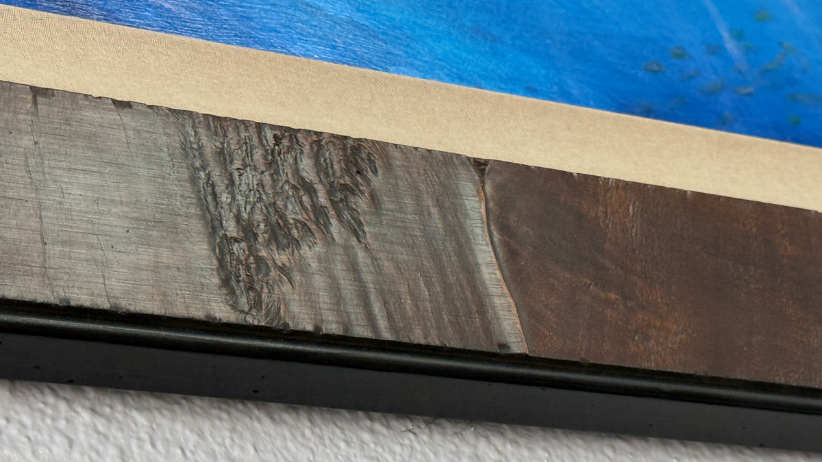Close-up of the textured dark wood frame and tan silk-covered liner on Peace of the Tropics