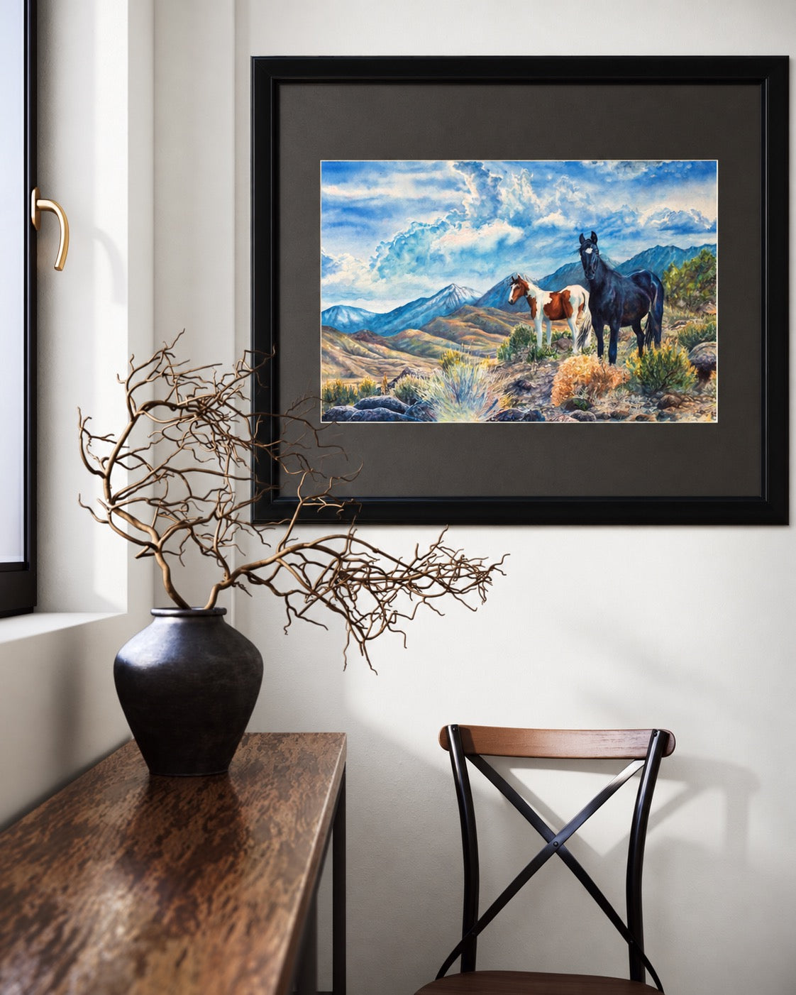 Interior visualization of Mustangs Wild framed watercolor displayed above a warm wood console with natural branches