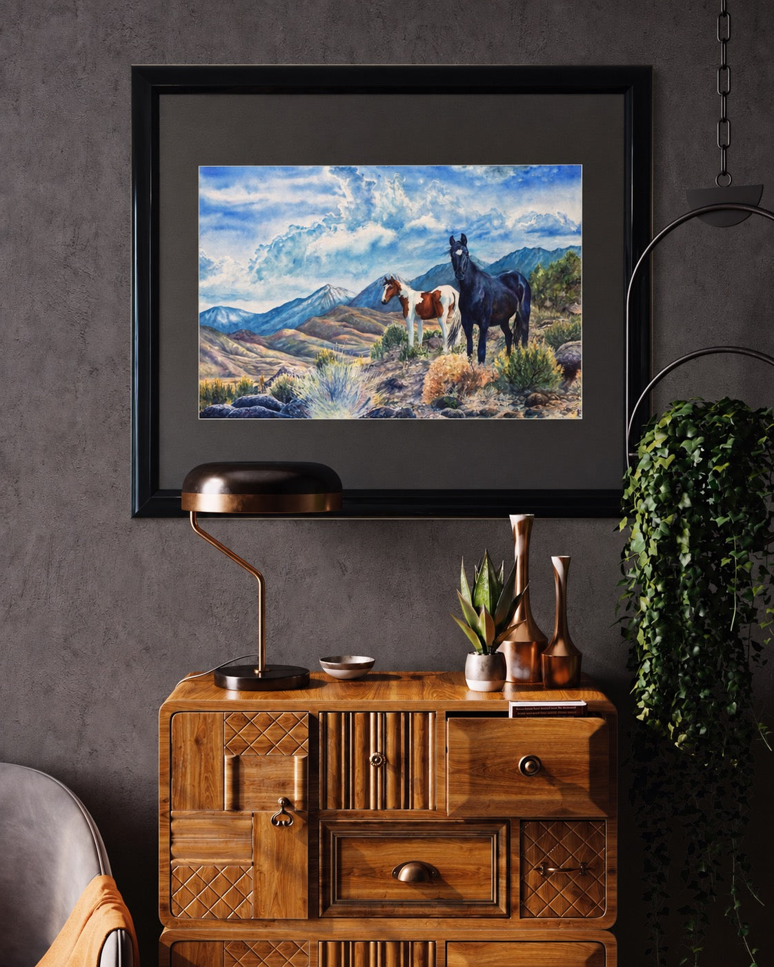 Interior visualization of Mustangs Wild framed wild horse watercolor displayed above a warm wood cabinet

