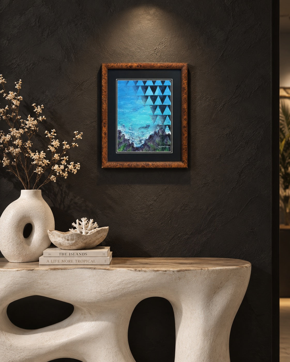 True-to-scale interior visualization of framed Mano Niho displayed on a dark textured wall above a sculptural console